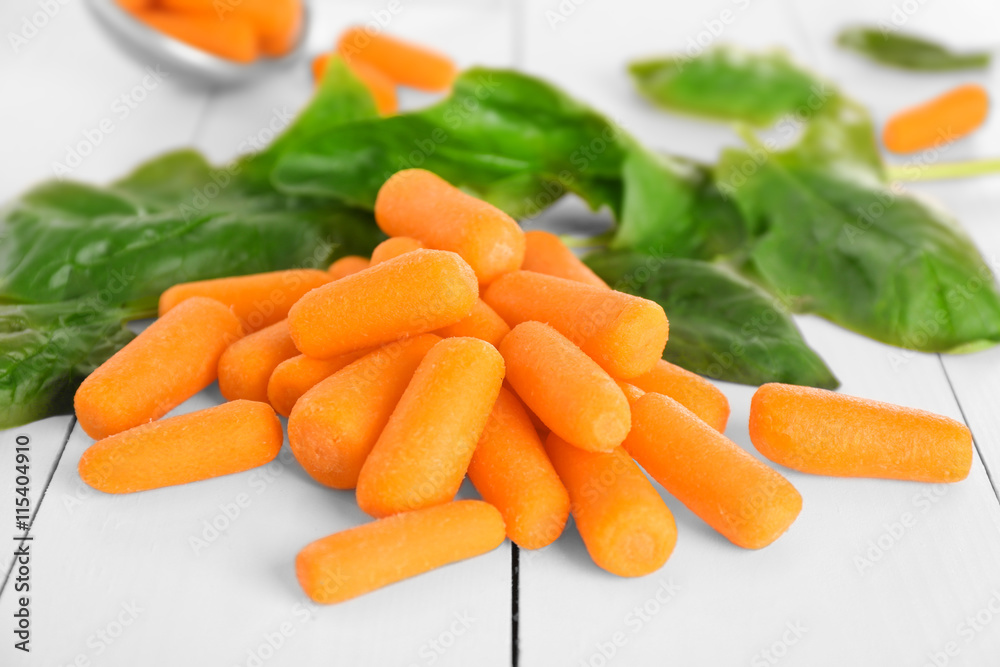 Heap of small baby carrots on wooden table Heap of small baby carrots on wooden table