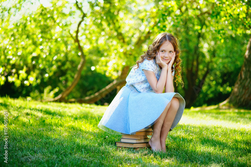 Little girl sitting on stack of books 
