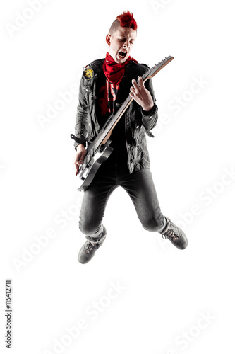 Wild teen boy with red haired mohawk playing guitar while jumping. Isolated