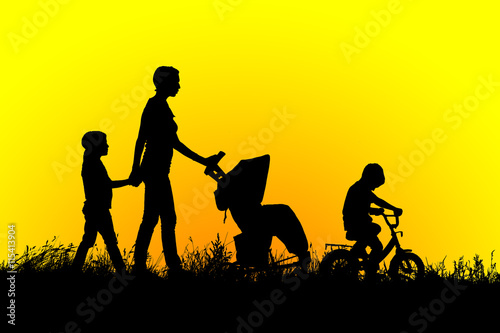 Mother with stroller and children walking at sunset