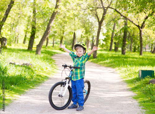 Fototapeta Naklejka Na Ścianę i Meble -  Portrait of a joyful child on a bicycle in a summer park