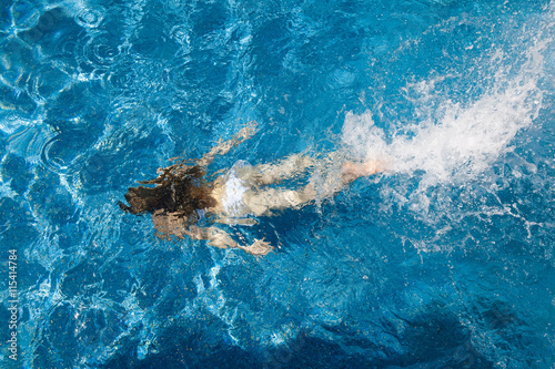 girl in a white bathing suit under the water in the pool