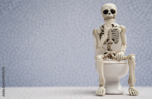 Skeleton thinking pose while sitting on water closet