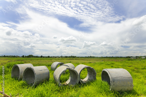 Concrete pipes on green meadow