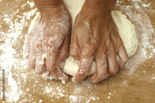 female hands knead dough on a board