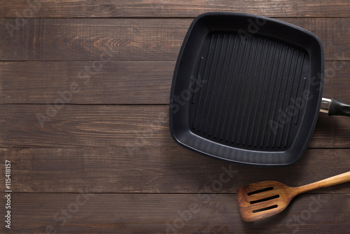 Cast iron frying pan and spatula on the wooden background. Copy