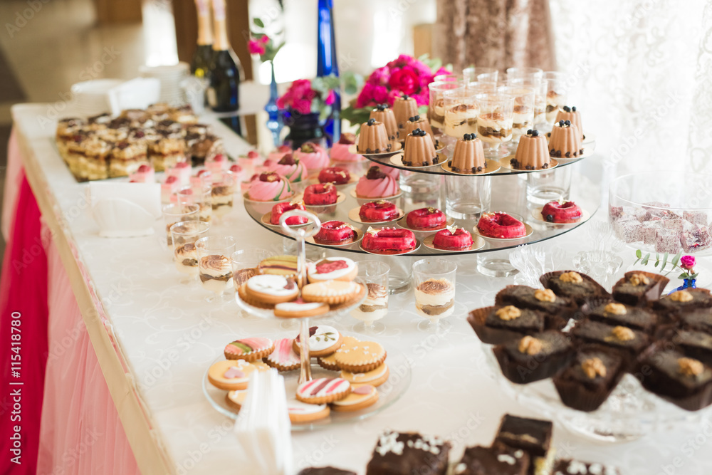 Delicious and tasty dessert table with cupcakes shots at reception closeup Delicious and tasty dessert table with cupcakes shots at reception closeup