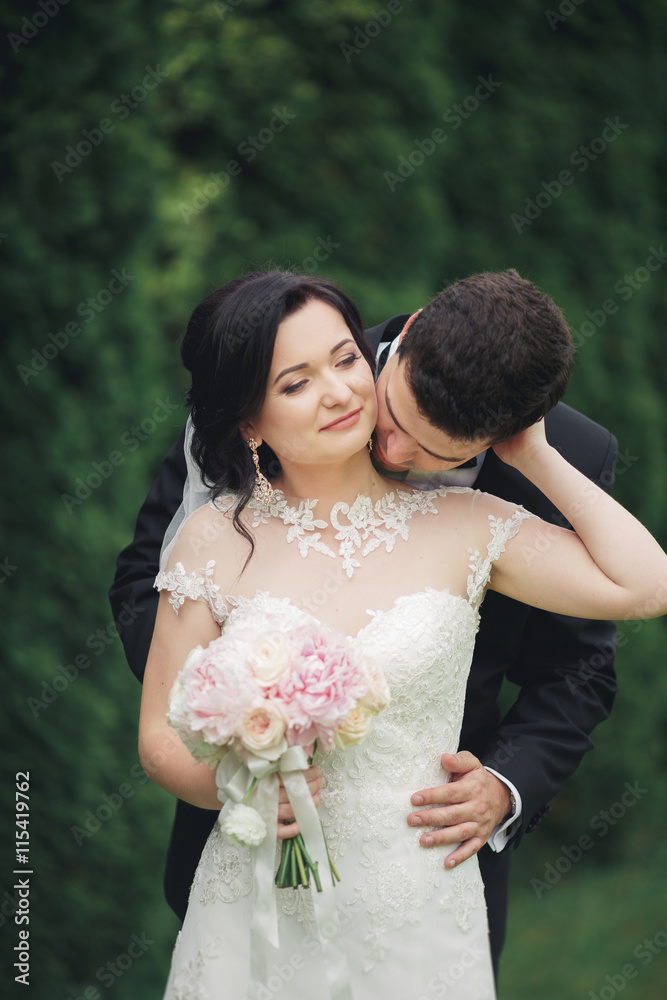Beautiful romantic wedding couple of newlyweds hugging in park on sunset Beautiful romantic wedding couple of newlyweds hugging in park on sunset