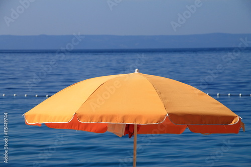 Orange beach umbrella near the Adriatic sea in Brela , Croatia