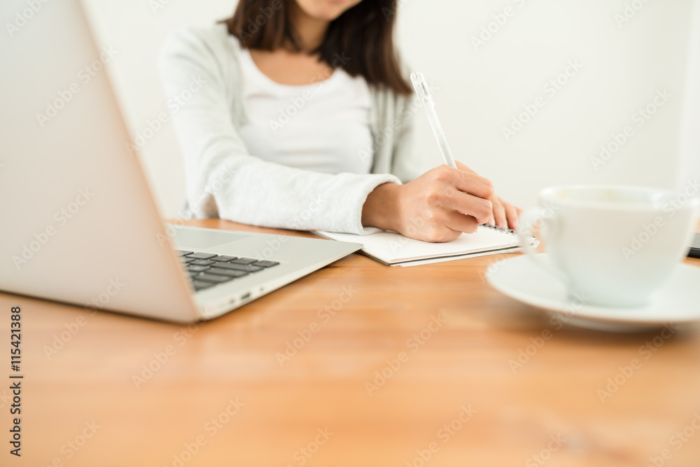 Woman writing on the note book on her desk Woman writing on the note book on her desk