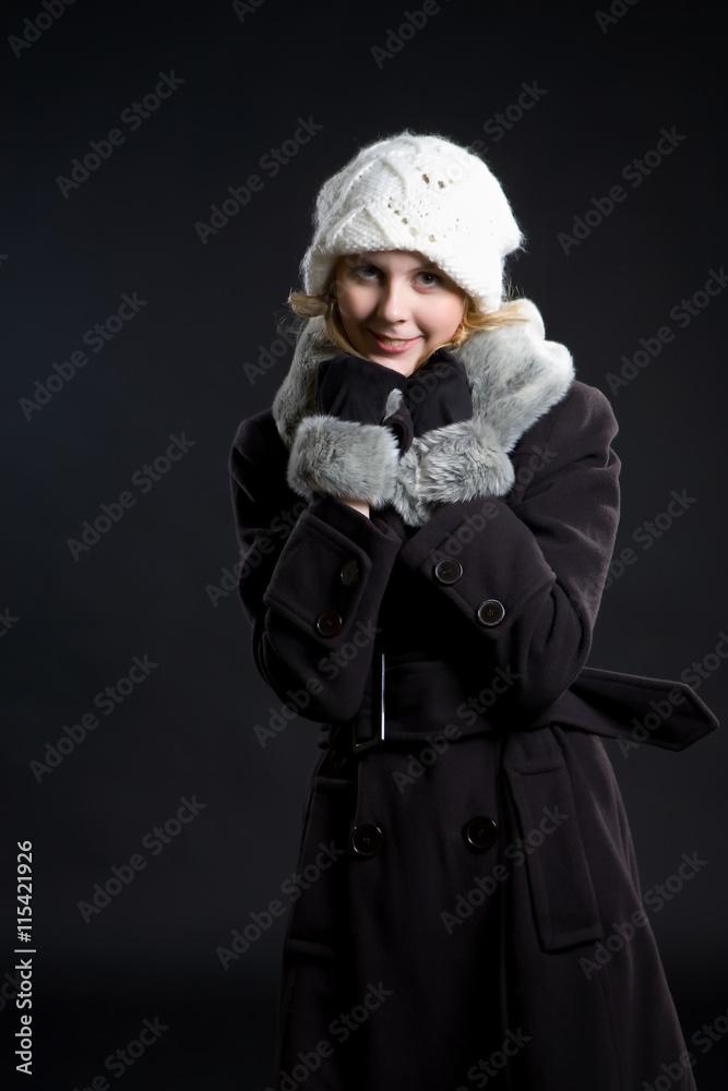 A girl in a gray coat with fur and a white cap.. A girl in a gray coat with fur and a white cap..