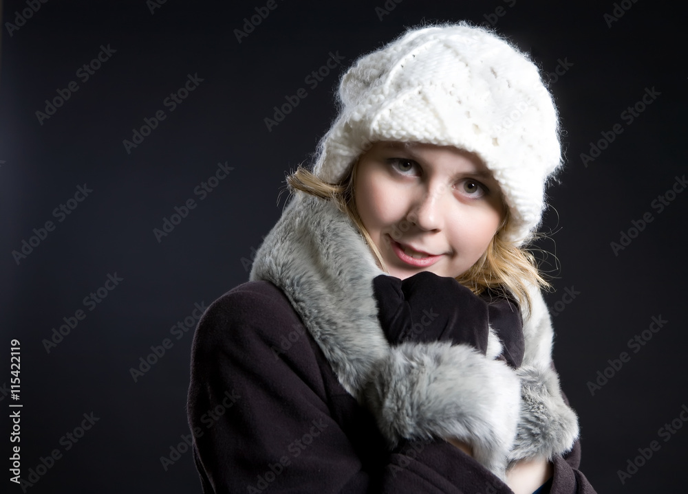 A girl in a gray coat with fur and a white cap.. A girl in a gray coat with fur and a white cap..