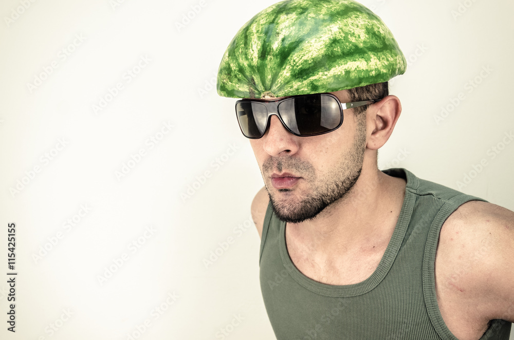 Fototapeta premium Funny man with a watermelon on his head. Hat covers the head