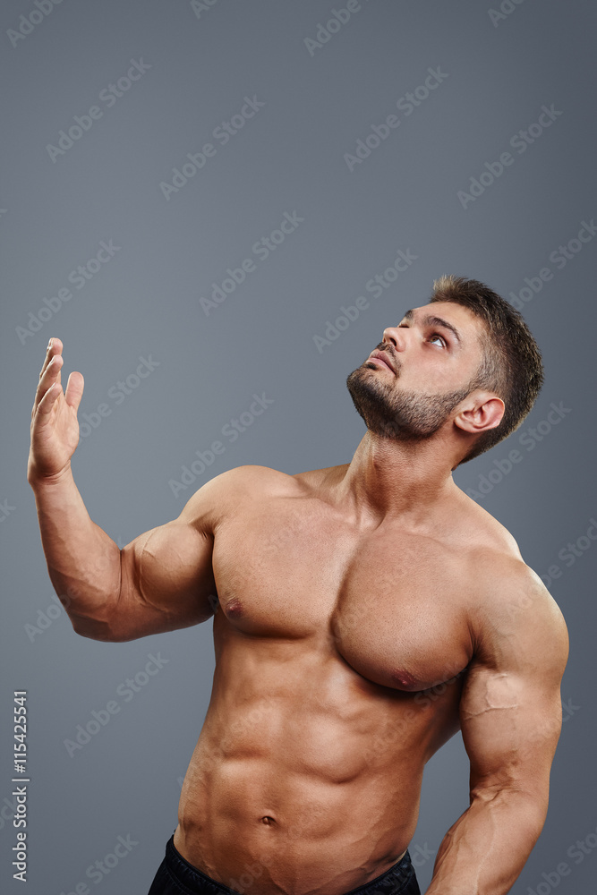 healthy athletic young man with muscle pointing up