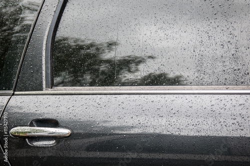 Water droplets on the glass. The surface of the black car in rain drops