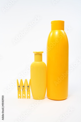Yellow plastic jars and clothespins on a white background