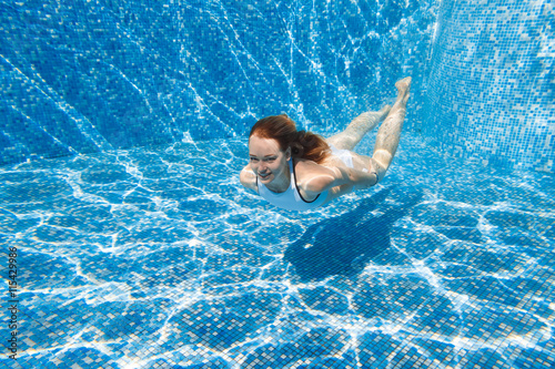 girl in the pool. She dives into the pool. Under water in a white bathing suit