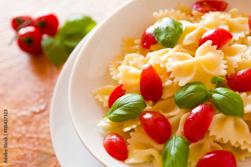 Closeup of Farfalle pasta with cherry tomatoes and basil over a