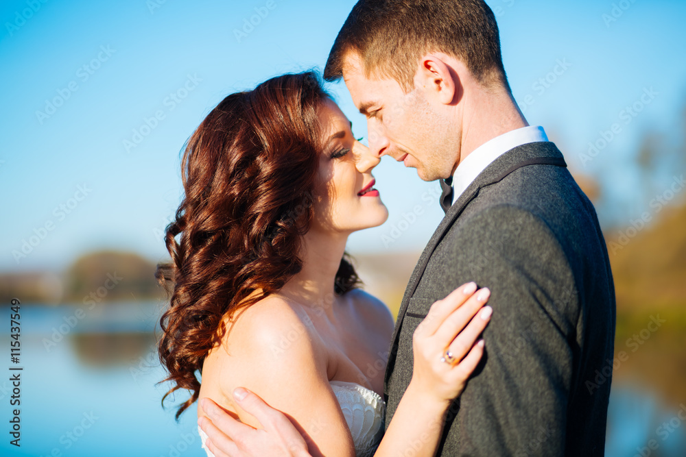 Kissing bride and groom in their wedding day near autumn tree Kissing bride and groom in their wedding day near autumn tree