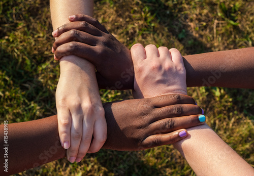 Hands of multiracial friends holding each other as team, cooperation concept