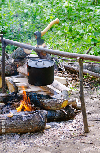 Tourist pot of water hanging over a fire of wood in the Camping