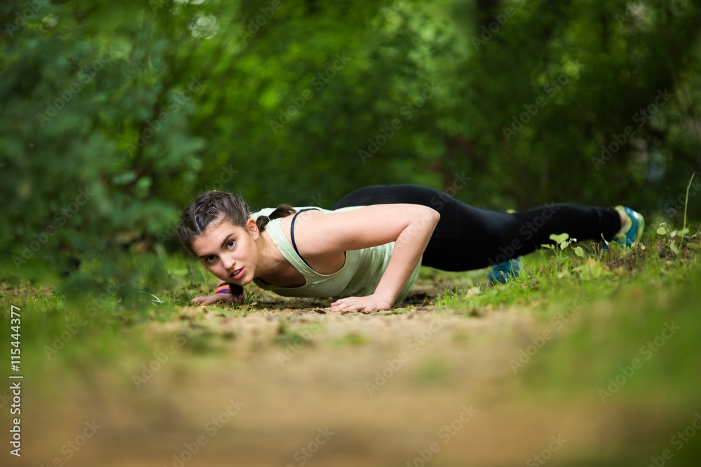 Fototapeta premium Beautiful young woman with braids exercising in the park.