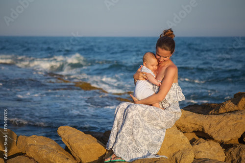 Mother and her son have fun at the sea beach at the sunset