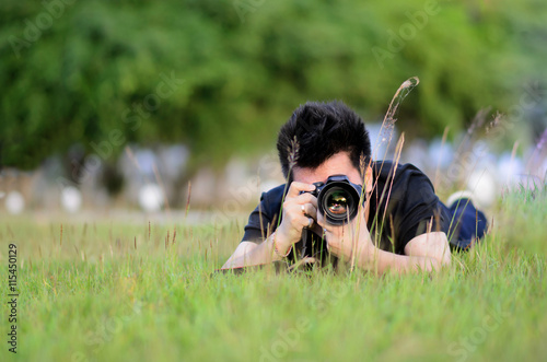 Smart man take a photo on field,lying on grass. photo