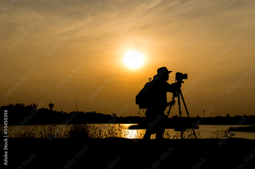 silhouette of photographer a lake on sunset.