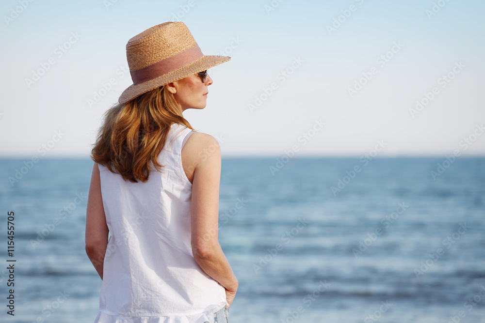 Peaceful and relaxing summer day at seaside. Mature woman standing on beach. Peaceful and relaxing summer day at seaside. Mature woman standing on beach.