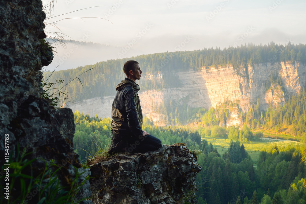 Man sitting on the top of the mountain and meeting sunrise