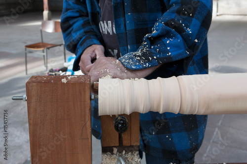 Man turns wood to make a chair leg