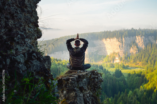 Man sitting on the top of the mountain in yoga pose