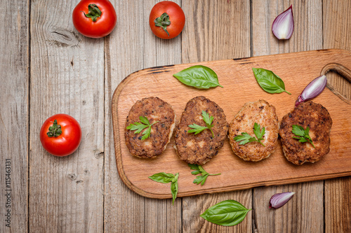 Fried pork burgers with tomatoes on the wooden board, top view