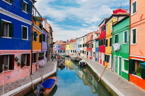 multicolored bright houses over canal with boats of Burano island, Venice, Italy