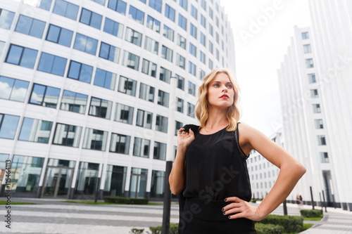 Blond woman in black standing near white buildings © snedorez