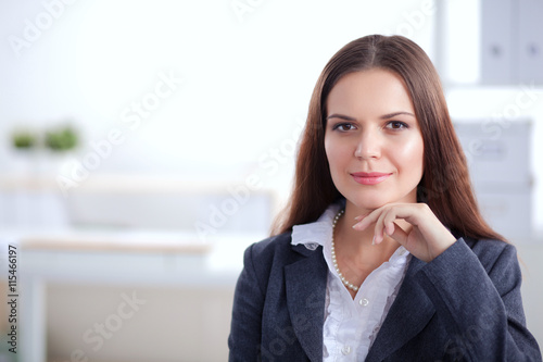 Attractive businesswoman sitting on desk in the office