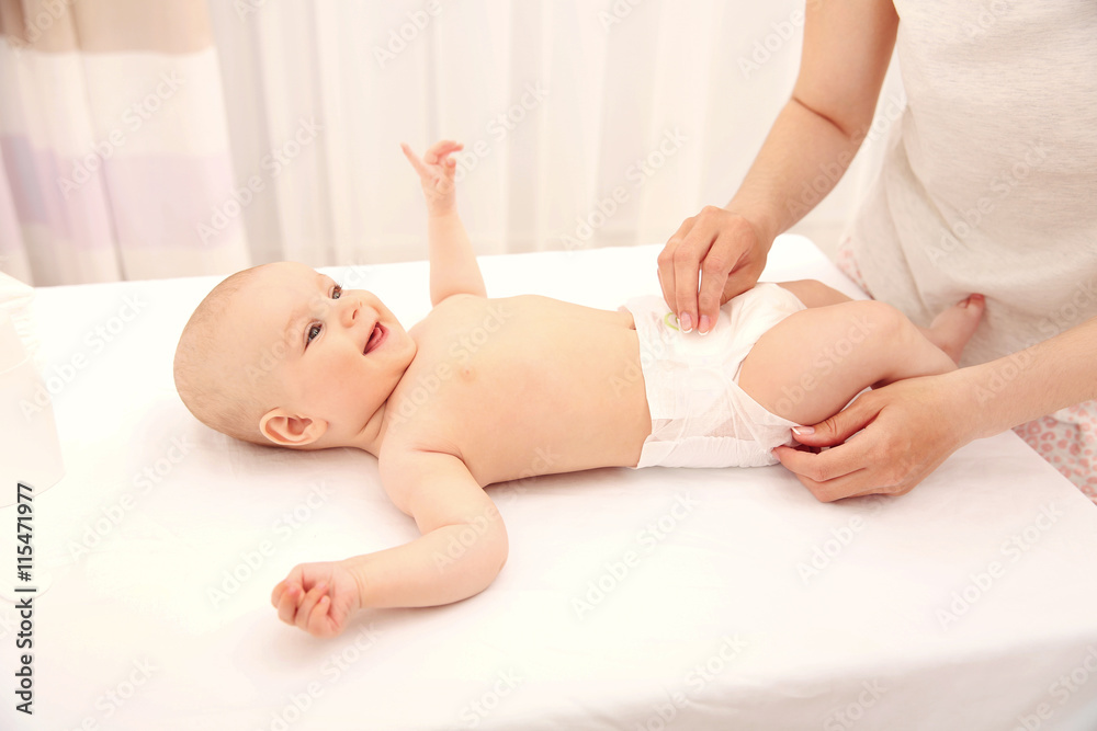 Mother changing diaper to little baby in room Mother changing diaper to little baby in room