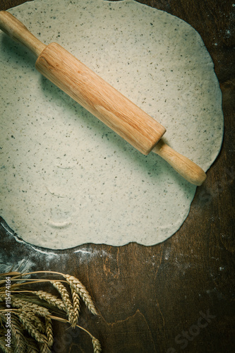 Wooden rolling pin with freshly prepared dough and dusting of fl