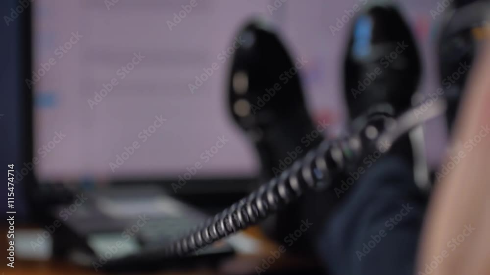 Businessman relaxed talking on the phone, feet up on the table Businessman relaxed talking on the phone, feet up on the table