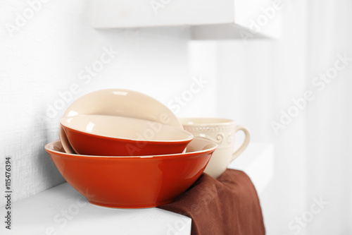 Set of tableware with napkin on shelf against white wall background