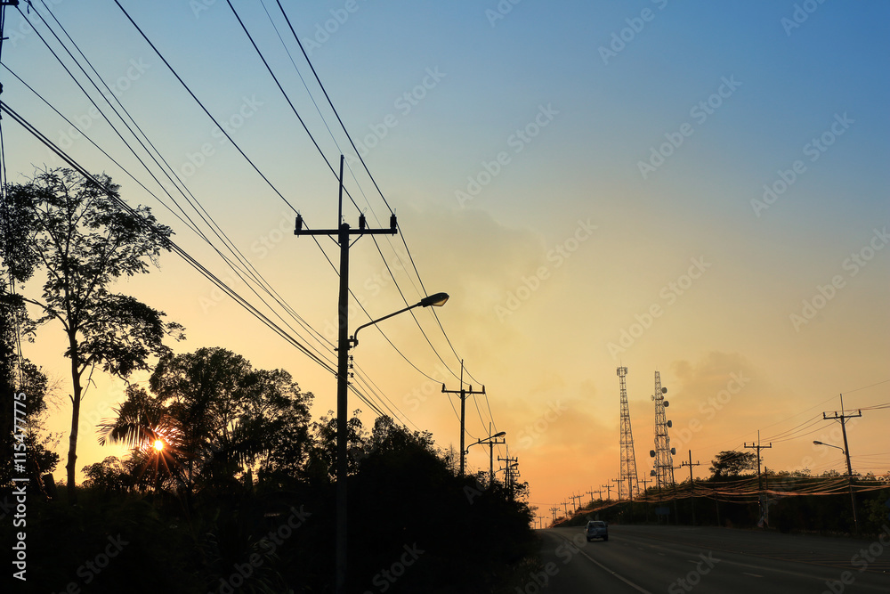 Sunset at the rural road with electrical pole and communication