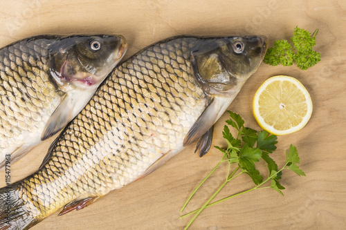 Fototapeta Naklejka Na Ścianę i Meble -  Fresh carps with lemon slice and herb on wood table