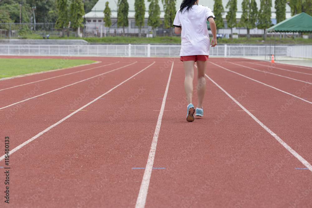 Fototapeta premium Young woman running on racetrack during training session. Asian