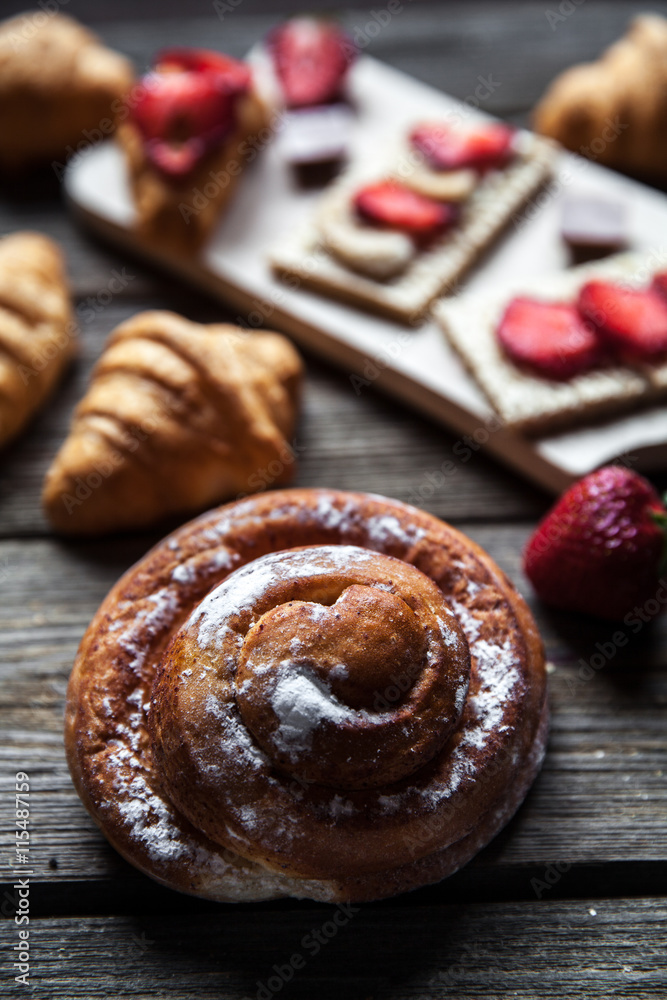 delicious breakfast with strawberries and sweet bun on wooden background. Fruit, food, chocolate delicious breakfast with strawberries and sweet bun on wooden background. Fruit, food, chocolate