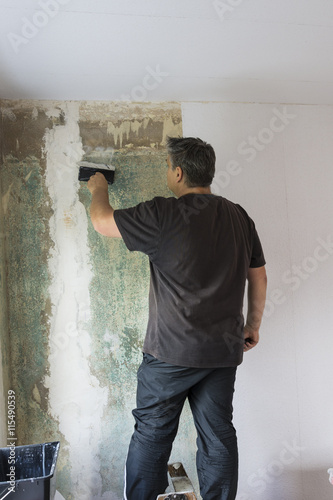 man hanging wallpaper. Decorating the wall