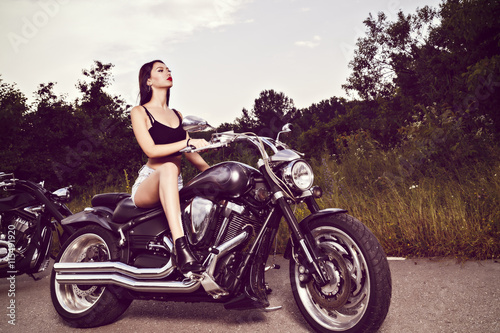 beautiful young woman posing with a motorcycle