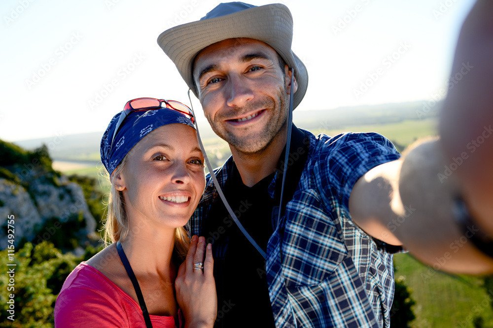 young couple on a hiking adventure trek making selfie with beautiful sunset landscape