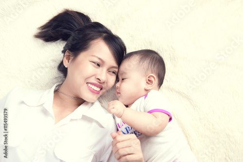 Portrait of beautiful mom playing with her 6 months old baby at home