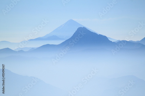 Two peaks in blue colour in high mountains during treking to the peak at dawn. Early morning clear blue sky. In the valley there is mist.